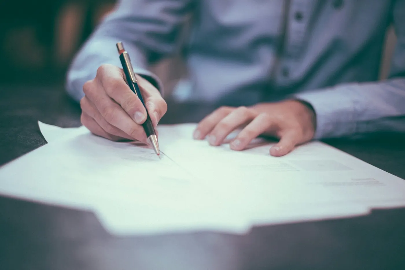 Person signing documents at a desk